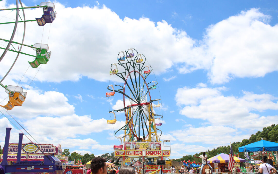 a colorful ferris wheel spins in front of a blue sky