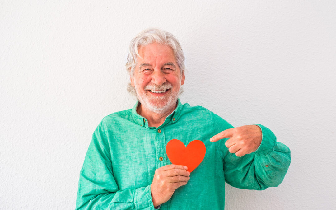 portrait of mature man smiling and looking at the camera with a red heart on his chest